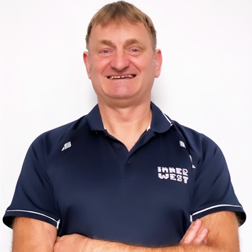 Personal trainer Michael standing with arms folded and smiling wearing a navy blue shirt branded with Inner West Aquatics logo